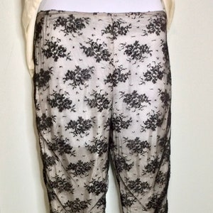 May include: Black lace pants with a floral pattern. The pants are made of a sheer fabric and have a loose fit.