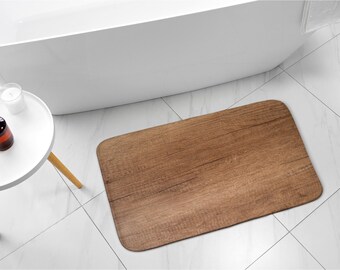 Könnte beinhalten: Eine braune Badezimmermatte in Holzoptik mit rechteckiger Form. Die Matte liegt auf einem weißen Fliesenboden.
