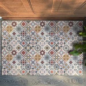 Puede incluir: Una alfombra de entrada estampada con un diseño geométrico en tonos azules, rojos, amarillos y blancos. La alfombra de entrada está hecha de un material duradero y es perfecta para agregar un toque de estilo a cualquier entrada.