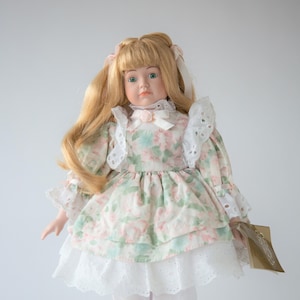 Vintage Franklin Heirloom Porcelain Doll featuring blonde hair and a green and pink floral dress