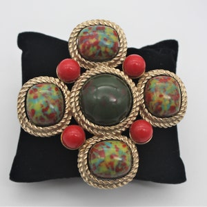 Beautiful vintage gold brooch by Sarah Coventry featuring green and red stones