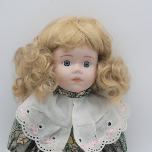 Adorable Vintage Porcelain doll with blonde curly hair and floral dress with lace and pink ribbon