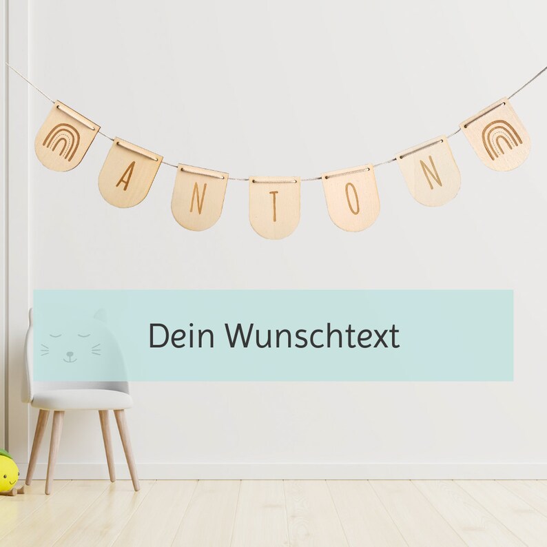 May include: Wooden banner with the name Anton and rainbow designs on each end. The banner is hanging on a white wall. The text "Dein Wunschtext" is on a light blue background below the banner.
