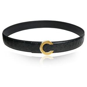 Puede incluir: Un cintur&oacute;n de cuero negro con un patr&oacute;n de piel de avestruz y una hebilla dorada en forma de C.