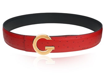 May include: A red leather belt with an ostrich skin pattern and a gold-toned G buckle.