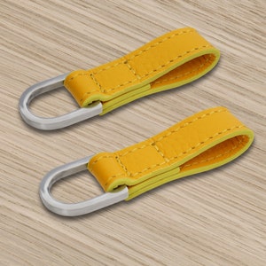 Peut inclure: Deux porte-clés en cuir jaune avec des boucles en métal argenté. Les porte-clés ont un design cousu et une bordure jaune contrastante.