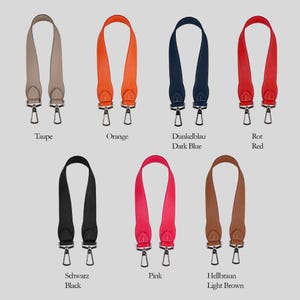 Può includere: Una collezione di sette cinturini in pelle per borse in vari colori, tra cui taupe, arancione, blu scuro, rosso, nero, rosa e marrone chiaro. Ogni cinturino ha chiusure in metallo color argento ed è etichettato con il nome del colore.