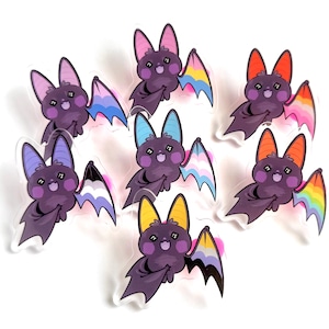 Peut inclure: Collection de sept autocollants de chauve-souris de dessin animé. Chaque chauve-souris violette a des ailes et des oreilles de couleurs différentes, notamment des motifs roses, bleus, oranges et arc-en-ciel. Les autocollants ont une finition brillante et un design mignon et amical.