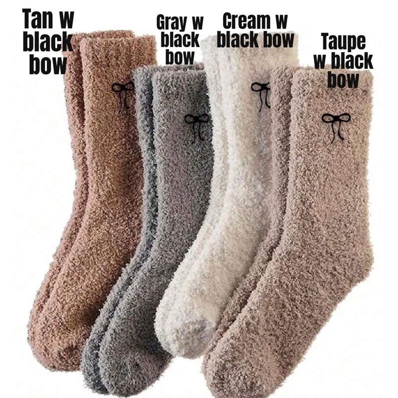 May include: Five pairs of fuzzy socks in various neutral colors: tan, gray, cream, and taupe. Each sock has a small black bow near the top. The text on the image reads "Tan w black bow", "Gray w black bow", "Cream w black bow", and "Taupe w black bow".