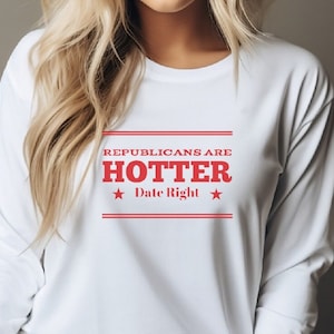 May include: White long-sleeved shirt with red text that reads "Republicans are Hotter Date Right" with a star on either side of the text.