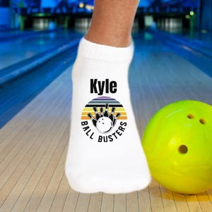 May include: White ankle socks with a bowling ball and pins graphic, the text "Ball Busters" and the name "Kyle" printed on them.