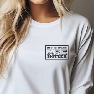 May include: White long-sleeve shirt with a black rectangular graphic. The graphic reads "REPUBLICANS ARE HOTTER" in a bold, stylized font. The shirt is made of a soft, comfortable material.