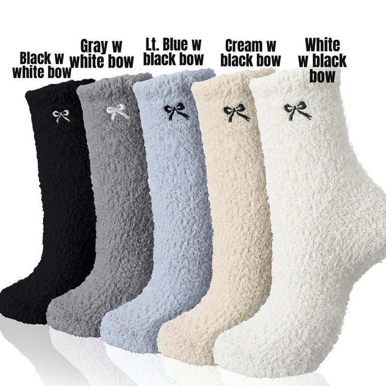 May include: A collection of knee-high fuzzy socks in various colors: black with a white bow, gray with a white bow, light blue with a black bow, cream with a black bow, and white with a black bow. Each sock has a bow detail.