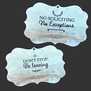 May include: Two rustic wooden signs with a distressed white paint finish. The top sign reads "NO SOLICITING No Exceptions" with a decorative flourish. The bottom sign reads "DON'T STOP Be leaving" with a star and a decorative flourish.