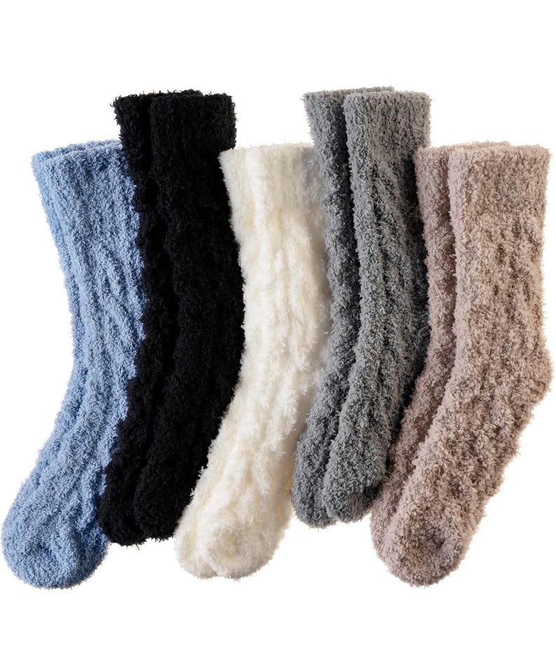 May include: A collection of six fuzzy socks in various colors: light blue, black, white, gray, and tan. The socks have a soft, textured appearance, suggesting a comfortable, warm material. The socks are arranged side by side.