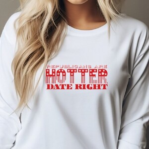 May include: White long-sleeved shirt with red text that reads "Republicans are Hotter Date Right". The text is in a bold font and has a red, white, and blue American flag design.