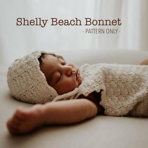May include: A sleeping baby wearing a cream-colored, crocheted bonnet and matching blanket. The text "Shelly Beach Bonnet - PATTERN ONLY -" is displayed in brown font at the top of the image. The baby is lying on a neutral-colored surface.