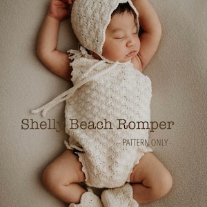 May include: A baby wearing a cream crochet romper, bonnet, and booties. The image includes the text "Shelly Beach Romper - PATTERN ONLY -". The baby is lying on a neutral-toned surface. The crochet outfit is a light, off-white colour.