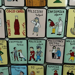 May include: A colorful wall display of illustrated cards with various professions and activities. Each card features a cartoon image and text in both Arabic and French. The professions include teacher, police officer, nurse, hairdresser, social worker, volleyball player, DJ, babysitter, firefighter, and lawyer.