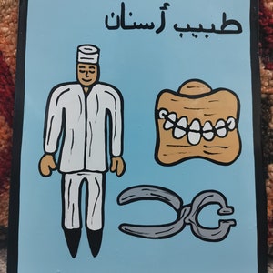 May include: A blue and white sign with the word "DENTIST" in black lettering. The sign also includes the Arabic word for dentist, "طبيب أسنان", in black lettering. The sign features a cartoon illustration of a dentist, a set of teeth, and a pair of pliers.