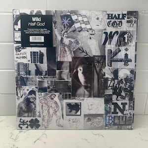 May include: A black and white collage album cover with the title "Wiki Half God" and the text "Produced entirely by Navy Blue" featuring Earl Sweatshirt, MIKE, duendita, Jesse James Solomon & Remy Banks. The cover features a variety of images, including a woman in a crown, a cat, and a checkered flag.