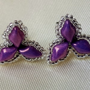 May include: A pair of purple and silver earrings with a three-leaf clover design.