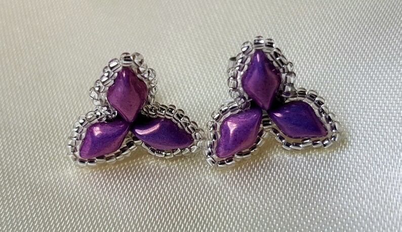 May include: A pair of purple and silver earrings with a three-leaf clover design.