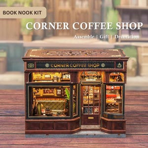 May include: A miniature Corner Coffee Shop book nook kit. The model features a detailed facade with windows, a door, and interior lighting. The sign reads "Corner Coffee Shop". The kit includes the text "Assemble | Gift | Decoration".