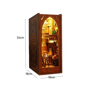 May include: A miniature wooden bookshelf diorama, 24cm tall, 18cm wide, and 10cm deep. The diorama is designed to look like a room with a balcony, a telescope, and a small table. The exterior is dark brown with the words "History of Books" on the side.