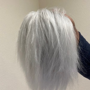 May include: A white wig with a short, choppy style. The wig is made of synthetic hair and has a natural-looking finish.