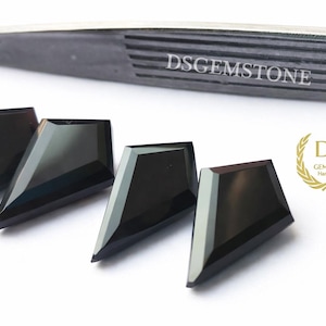 May include: Four black shield-shaped faceted gemstones arranged in a row. Above the stones is a pair of dark metal tweezers with the text DSGEMSTONE engraved. To the right is a gold laurel wreath logo with the text DS GEMSTONE Handmade.