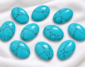 May include: Ten oval-shaped turquoise cabochons with a smooth, polished finish. Each stone features a vibrant cyan blue colour with distinct, dark black spiderweb matrix veining patterns distributed across the surface of the stones.
