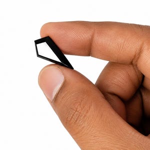 May include: A small, black, geometric object with a pointed top and a hollow, angular center. The item is constructed from thin, rigid material and features a sharp, symmetrical silhouette that forms a diamond-like shape with an open interior space.