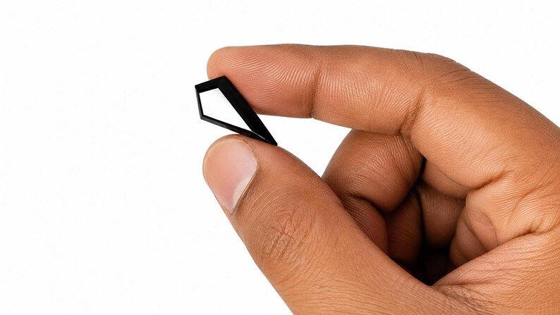 May include: A small, black, geometric object with a pointed top and a hollow, angular center. The item is constructed from thin, rigid material and features a sharp, symmetrical silhouette that forms a diamond-like shape with an open interior space.