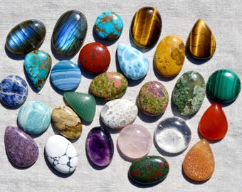 Peut inclure: Une collection de vingt-six pierres précieuses cabochons polies de formes et de couleurs variées, incluant de la labradorite bleue, de la turquoise, de l'œil-de-tigre, du jaspe rouge, de la malachite verte, de l'améthyste, du quartz rose et de la cornaline.