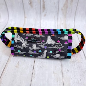 May include: A black pencil case with a zipper closure and a colorful rainbow striped trim. The case features a repeating pattern of seals, ice floes, and colorful dots. The text "hidden gems oddities" is printed on the case.
