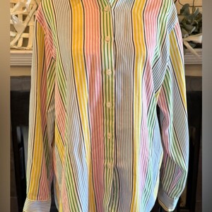 May include: A button-down shirt with vertical stripes in yellow, pink, green, black, and blue. The long-sleeved shirt has a collared neckline and buttoned cuffs. The shirt is displayed on a mannequin.