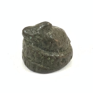 May include: A small, dark green, ceramic sculpture of a curled-up animal, possibly a mouse or a frog.