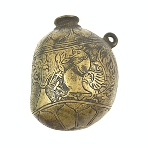 May include: A small, gold-colored, round, metal container with an intricate design. The container has a loop on the top and is decorated with a floral pattern and a bird.