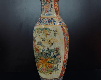May include: A large, white ceramic vase with a floral and bird design. The vase has a wide mouth and a narrow neck. The design features peacocks, flowers, and birds in shades of blue, green, red, and yellow.