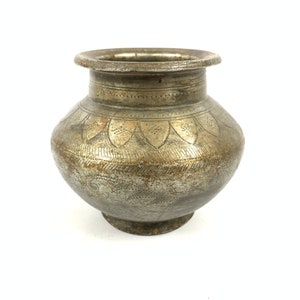 May include: A silver metal pot with intricate etched designs. The pot has a round body and a wide, flat base.