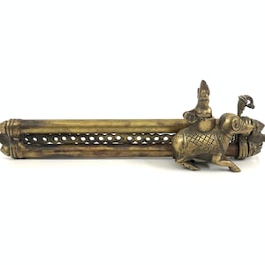 Könnte beinhalten: Ein Messing-Räucherofen mit dekorativem Design. Der Räucherofen zeigt eine Figur, die auf einem Stier reitet, mit aufwendigen Details und einem langen, hohlen Körper.