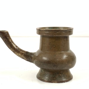 Op de afbeelding: Een klein, bruin, metalen theepotje met een tuit en een rond lichaam. De theepot heeft een licht verweerde afwerking.