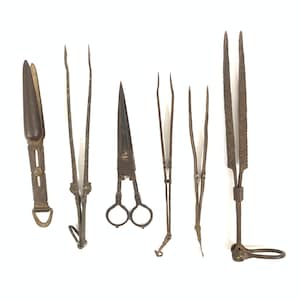 May include: Set of six antique metal tools, including tweezers, scissors, and a pair of pliers. The tools are all made of a dark metal and have a rustic appearance.