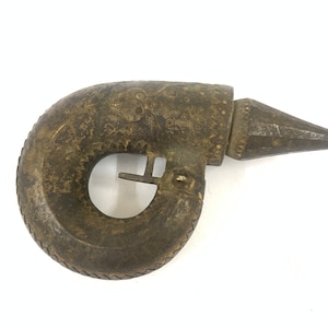 May include: A vintage, ornate, metal,  hand-held,  gun-shaped object with a  decorative design. The object has a  curved handle and a  pointed end.