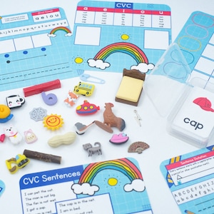 May include: A set of colorful CVC (consonant-vowel-consonant) learning materials for kids. The set includes a variety of colorful toys, a rainbow, a bed, a school bus, a cap, and a sentence card with the words "The cap is in the net".