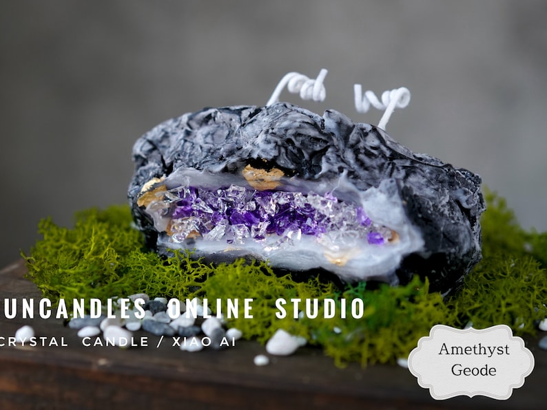 Pu&ograve; includere: Una candela nera e bianca a forma di geode con un interno di cristallo di ametista viola. La candela &egrave; appoggiata su un letto di muschio verde e pietre bianche. Il testo "UNCANDLES ONLINE STUDIO" e "CRYSTAL CANDLE / XIAO AI" &egrave; visibile sotto la candela. Il testo "Ametista Geode" &egrave; visibile in una forma ovale bianca nell'angolo in basso a destra dell'immagine.