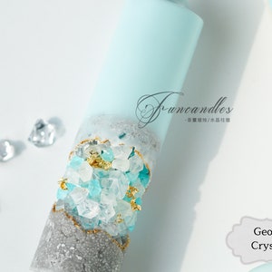 May include: A blue and gray candle with embedded crystals and gold flakes. The candle is labeled "Funcandles - 香薰蠟燭/水蠟燭". The text "Geode Crystal" is also visible in the image.