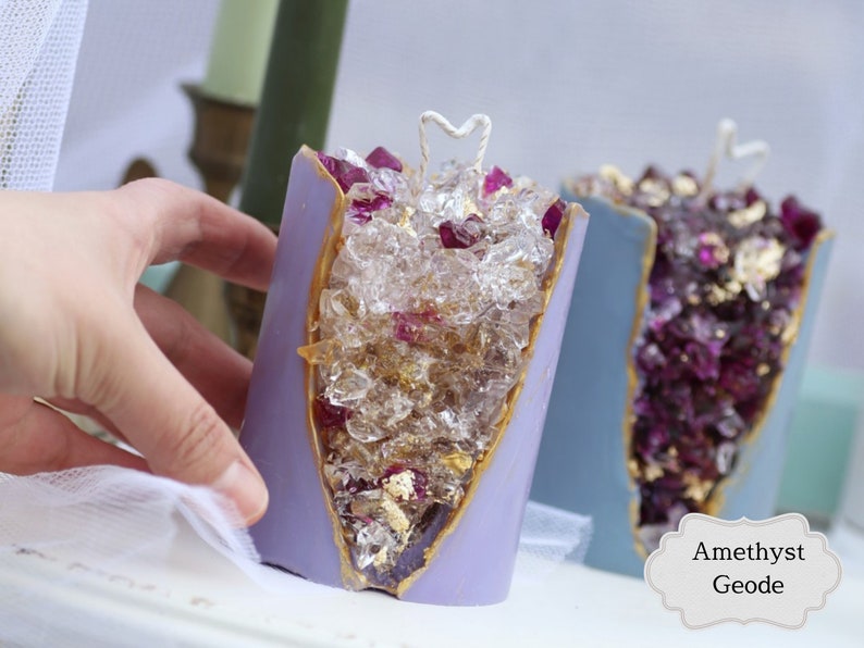 Peut inclure: Deux bougies en forme de g&eacute;ode d'am&eacute;thyste violette avec des accents dor&eacute;s et des cristaux transparents &agrave; l'int&eacute;rieur. Les bougies ont une m&egrave;che en forme de c&oelig;ur blanc.