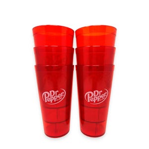 May include: A set of six stackable, translucent red plastic tumblers arranged in two columns of three. Each tumbler features the white Dr. Pepper logo with the text Est. 1885 printed on the front. The cups have a tapered design with horizontal ridges.